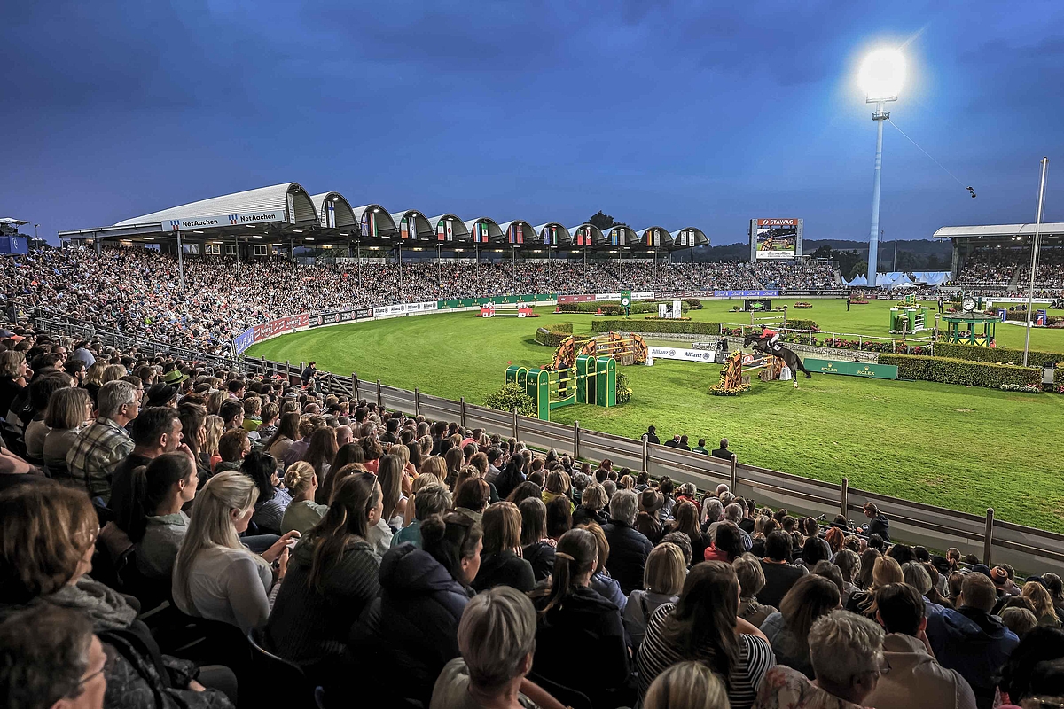 Zuschauerränge und Reiter beim Springreiten