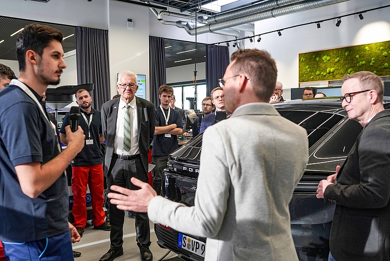 Gruppe von Menschen vor einem Auto in einer modernen Werkstatt