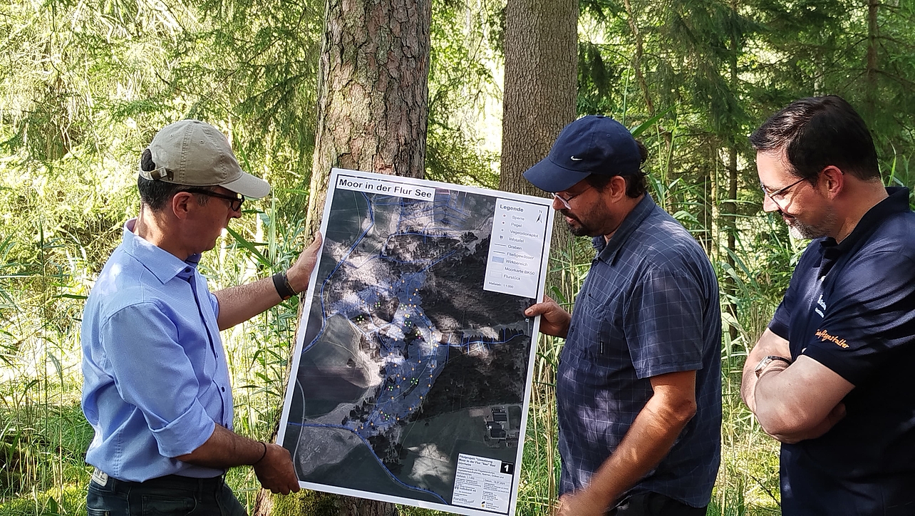 3 Personen mit einer Moorlandkarte im Wald